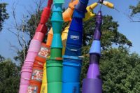 A photo of a rainbow sculpture made of plastic paint buckets.