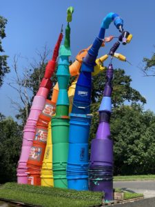 A photo of a rainbow sculpture made of plastic paint buckets.